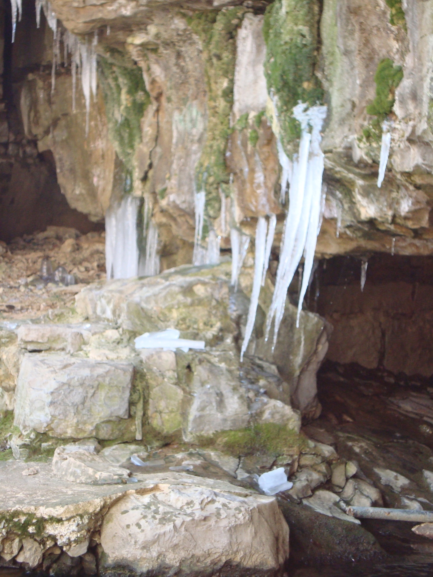 Icicles hanging from rocky outcrops in a cave-like environment.