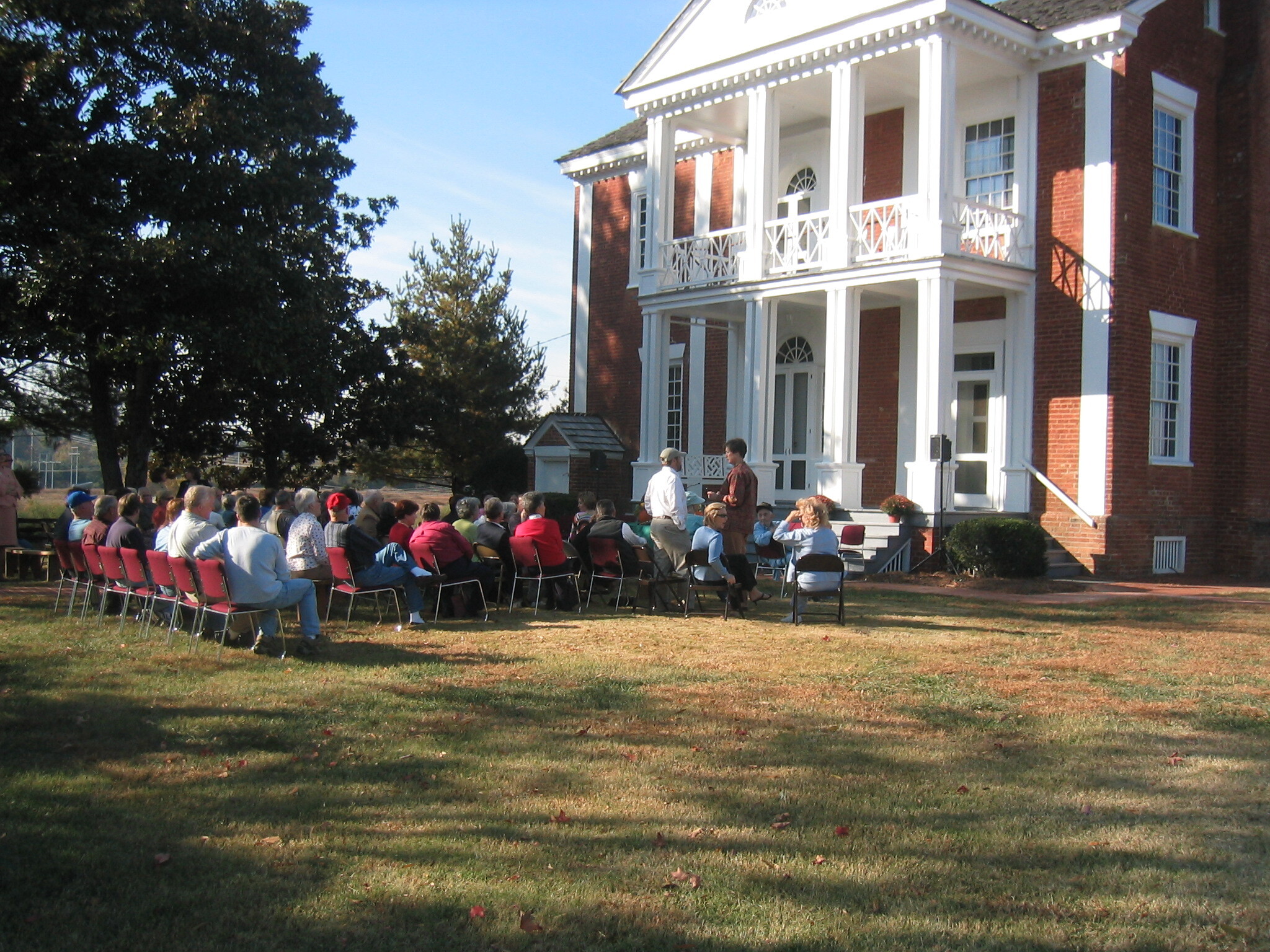 A group of people are gathered in front of a house.