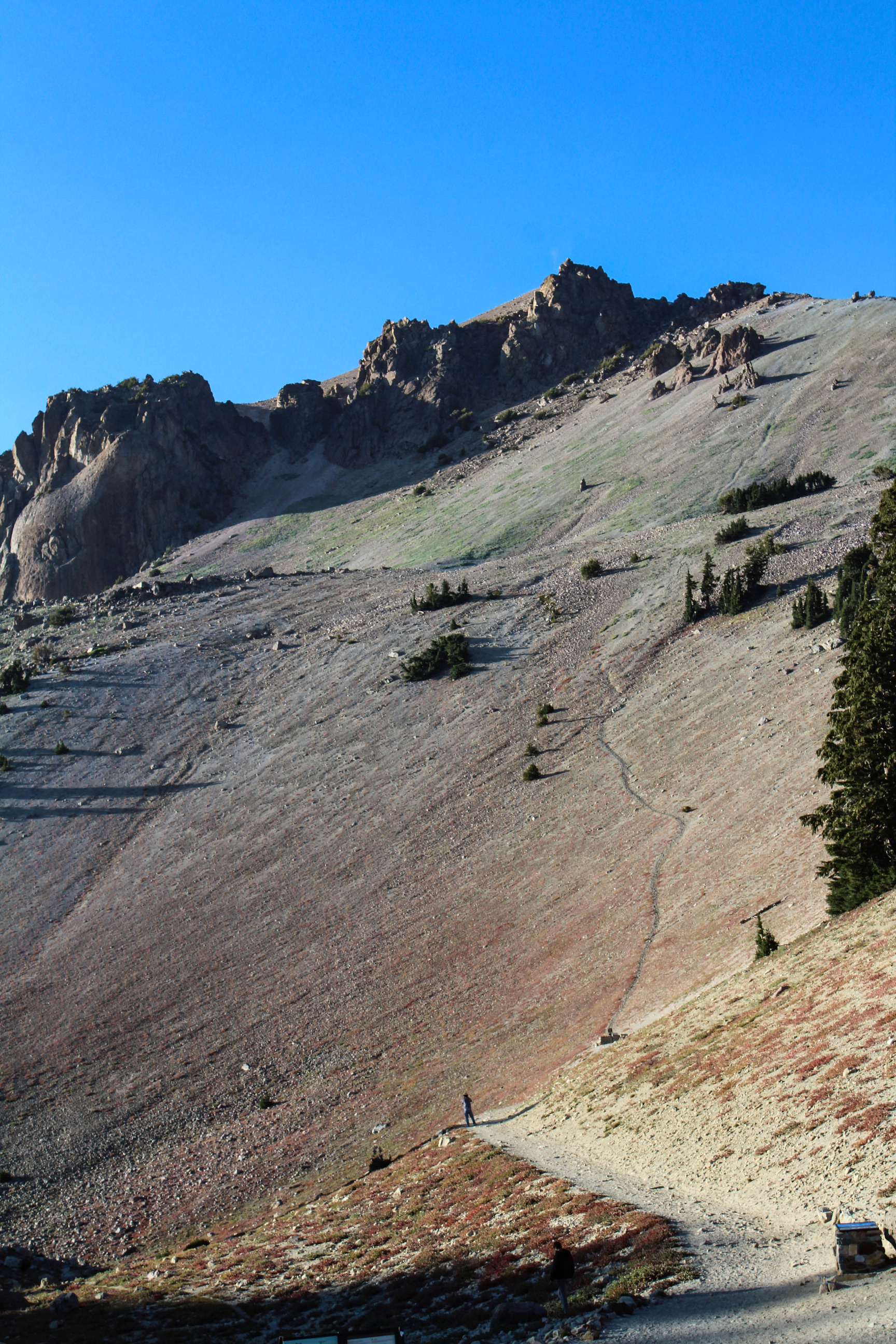 Person on a trail leading up a tall peak