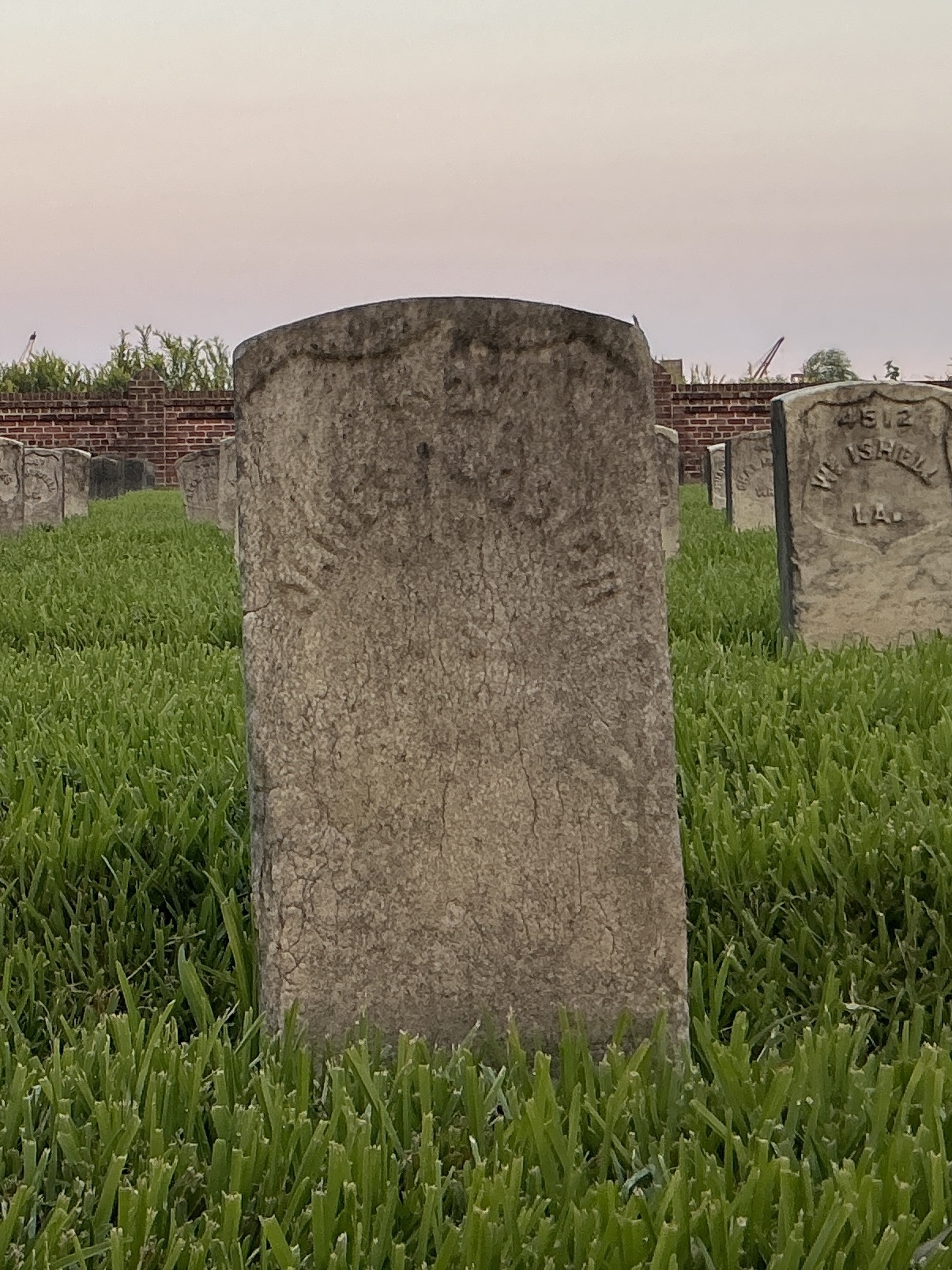 Front of historic upright marble headstone with recessed shield face.