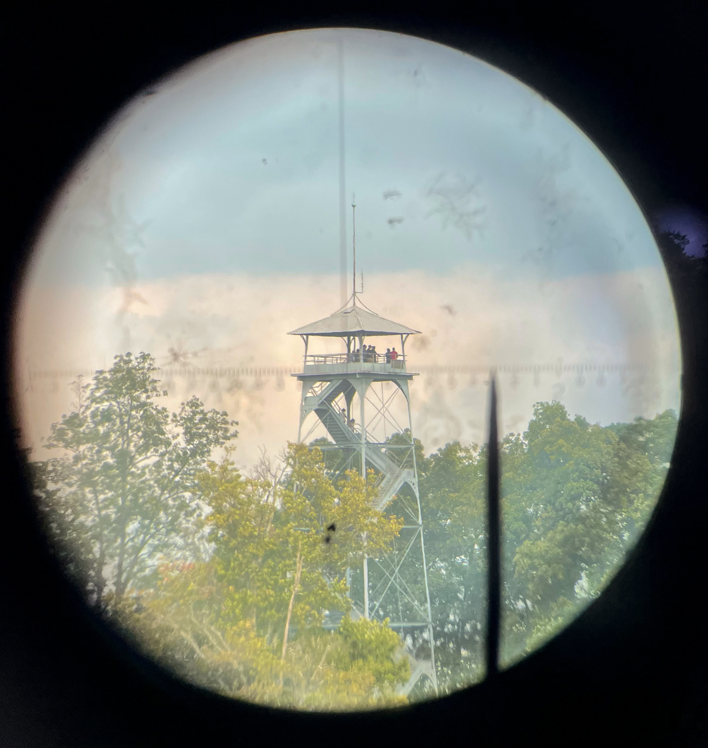 A view through a black circular scope of a metal tower.