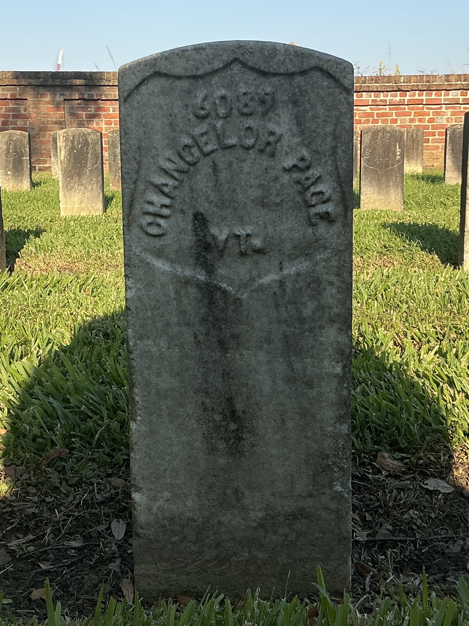 Front of historic upright marble headstone with recessed shield face.
