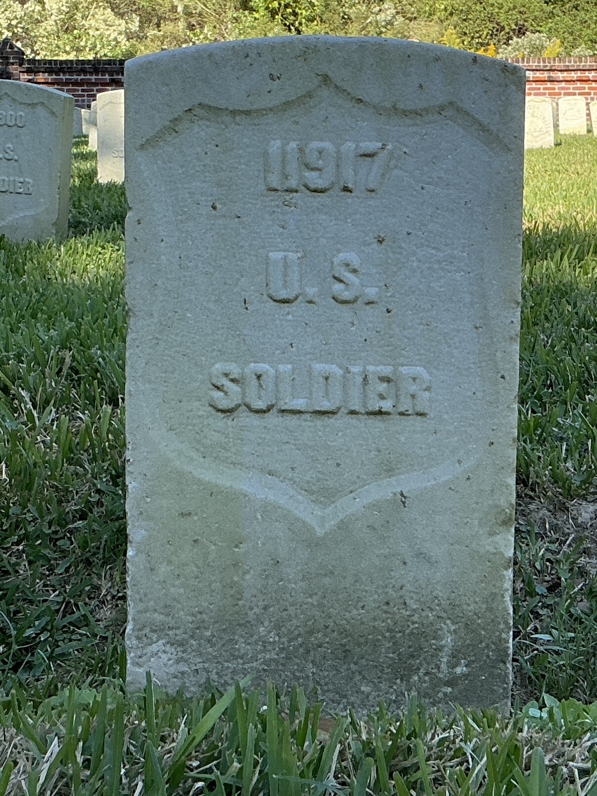 Front of historic upright marble headstone with recessed shield face.