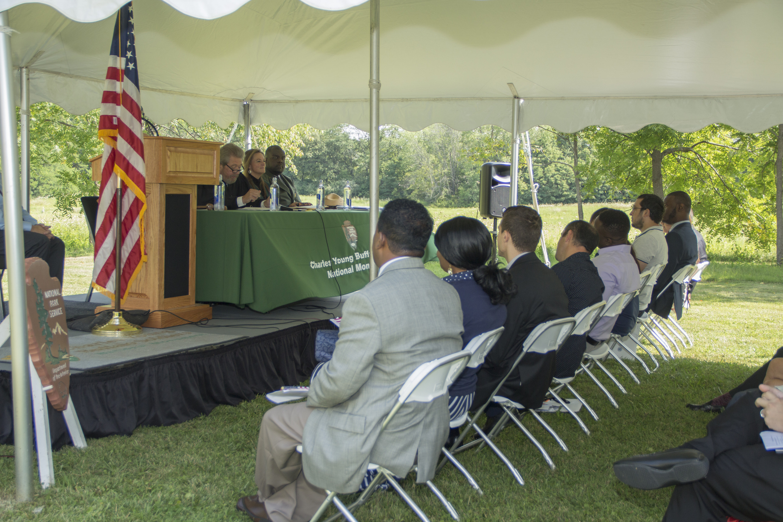 Several people looking up at others sitting at a green table.