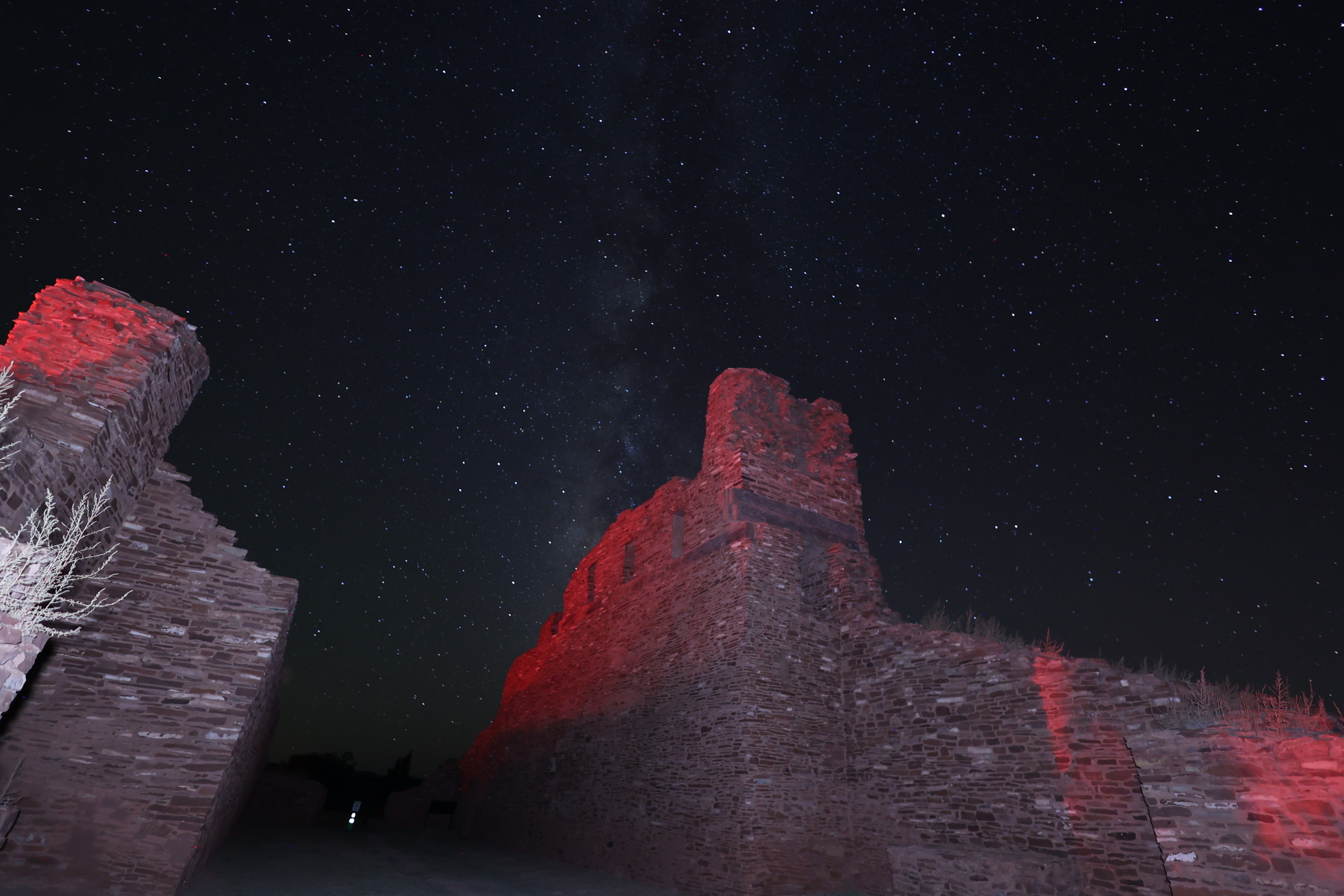 Milky Way in a starry sky with red sandstone church remnants in the foreground.