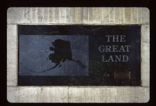 Stone of Jade with bronze plaque and black letters that shows the state of Alaska with the words THE GREAT LAND
