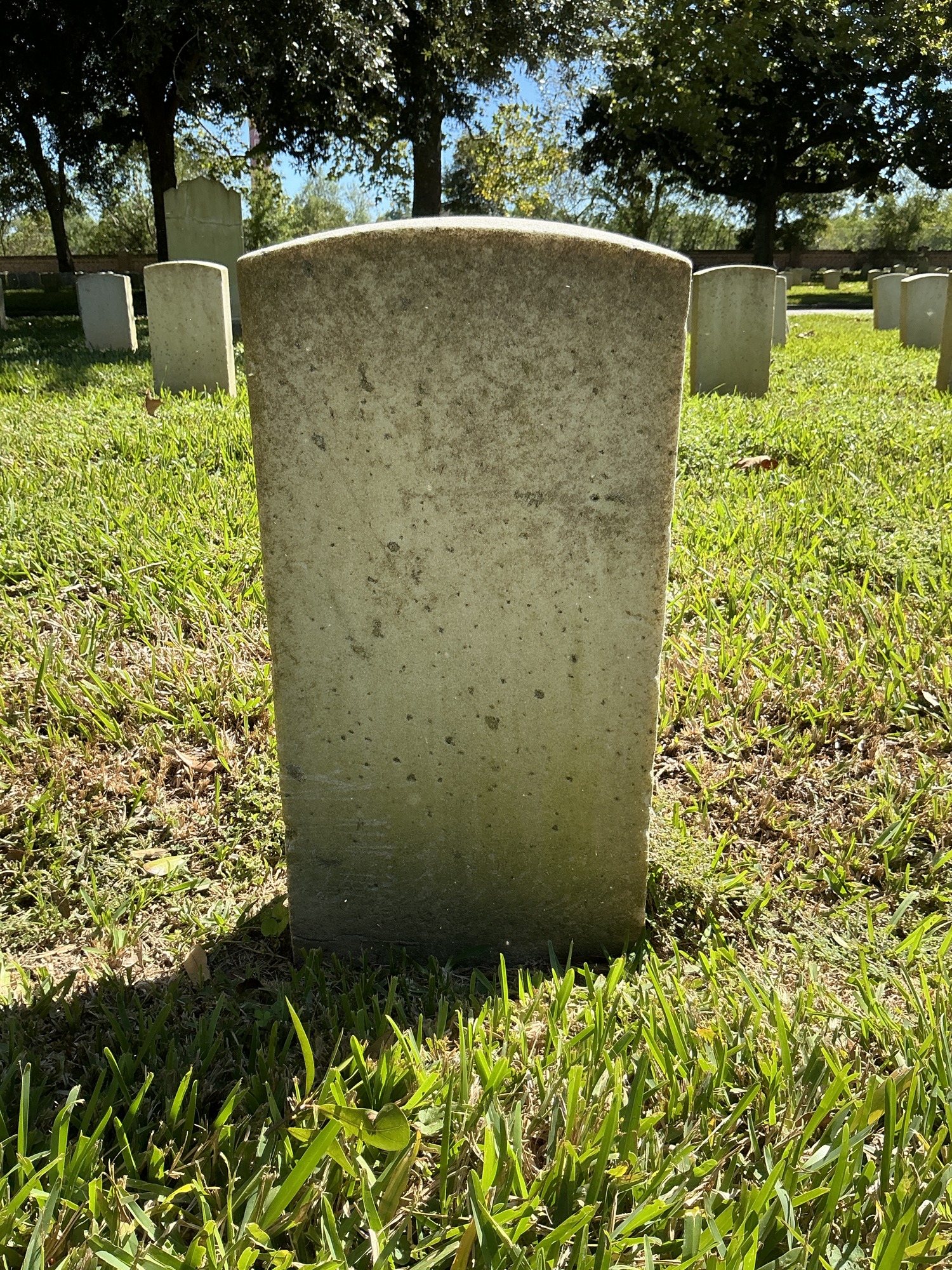 Back of historic upright marble headstone with recessed shield face.