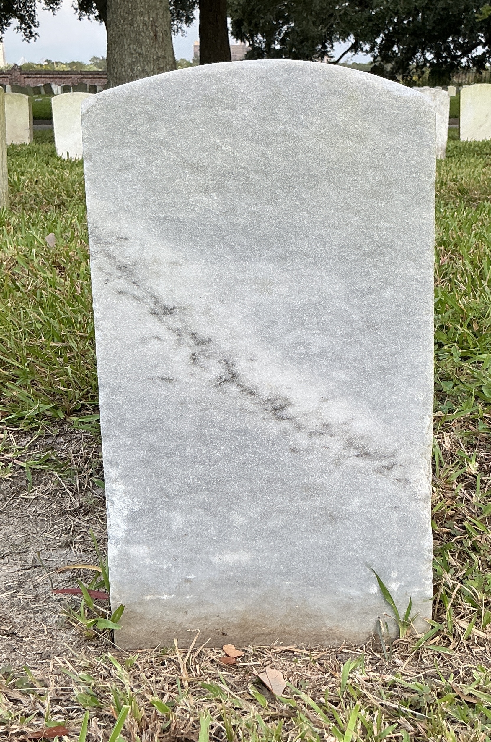Back of historic upright marble headstone with recessed shield face.