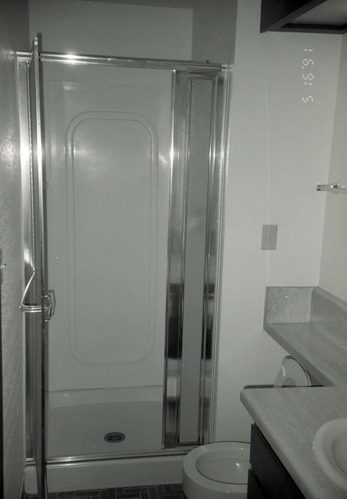 Shower in bathroom of barracks. [Image possibly for comparative housing study]