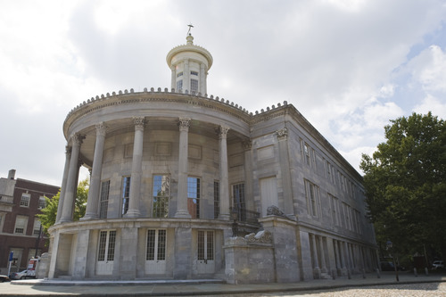 Color photo showing rounded facade of marble building with seven columns and a lantern tower.