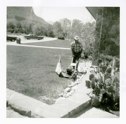 Man mowing the lawn of the old Mission 66 Visitor Center and Museum grounds.