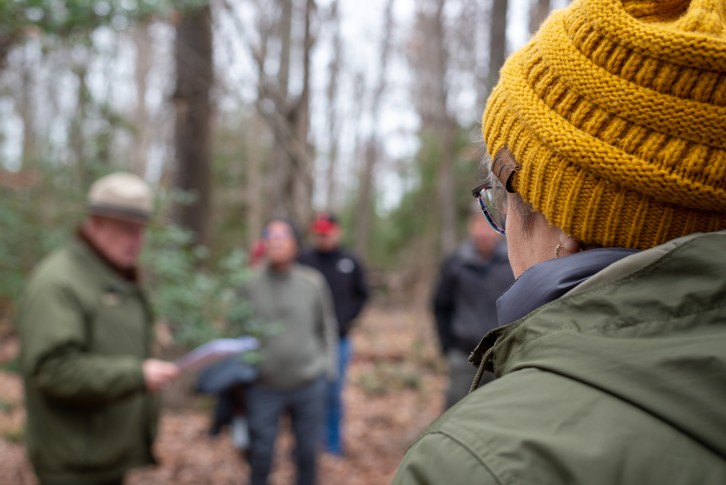 A woman in a yellow hat looking at a park ranger.