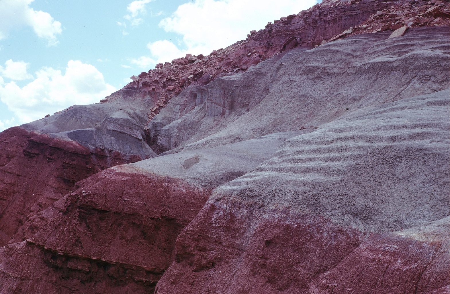 Two distinct rock layers, with the lower one being a dark red and the upper a gray-green. Both have a soft, lumpy look. 