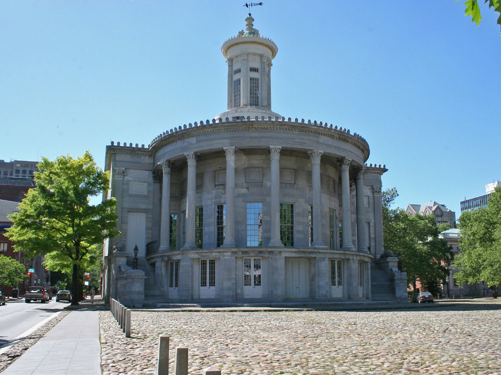 Color photo showing rounded facade of gray marble building with seven columns and a lantern tower.