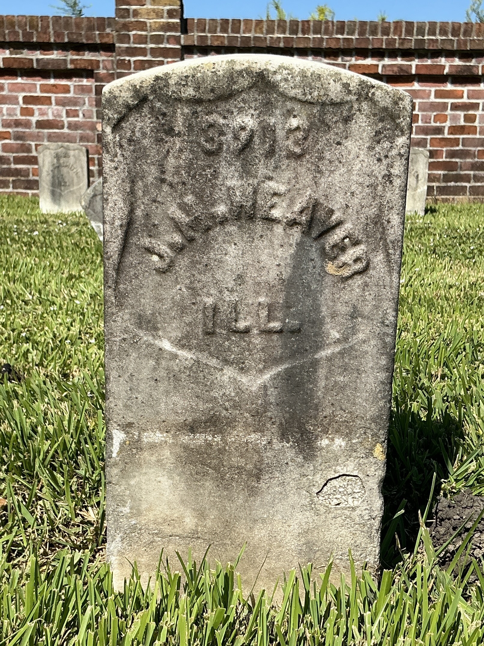 Front of historic upright marble headstone with recessed shield face.