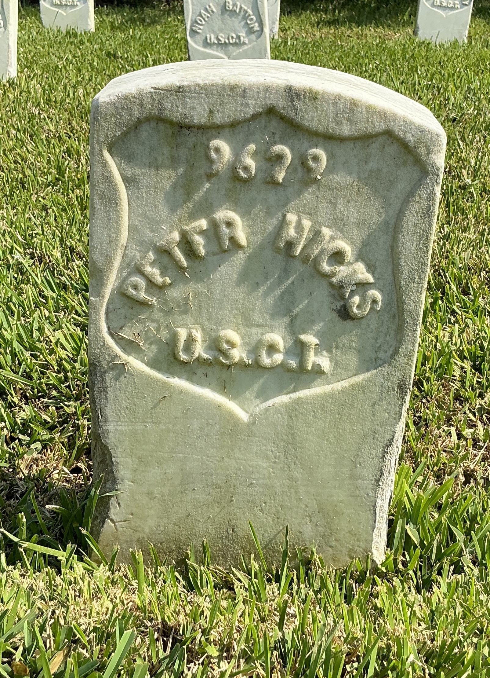 Front of historic upright marble headstone with recessed shield face.
