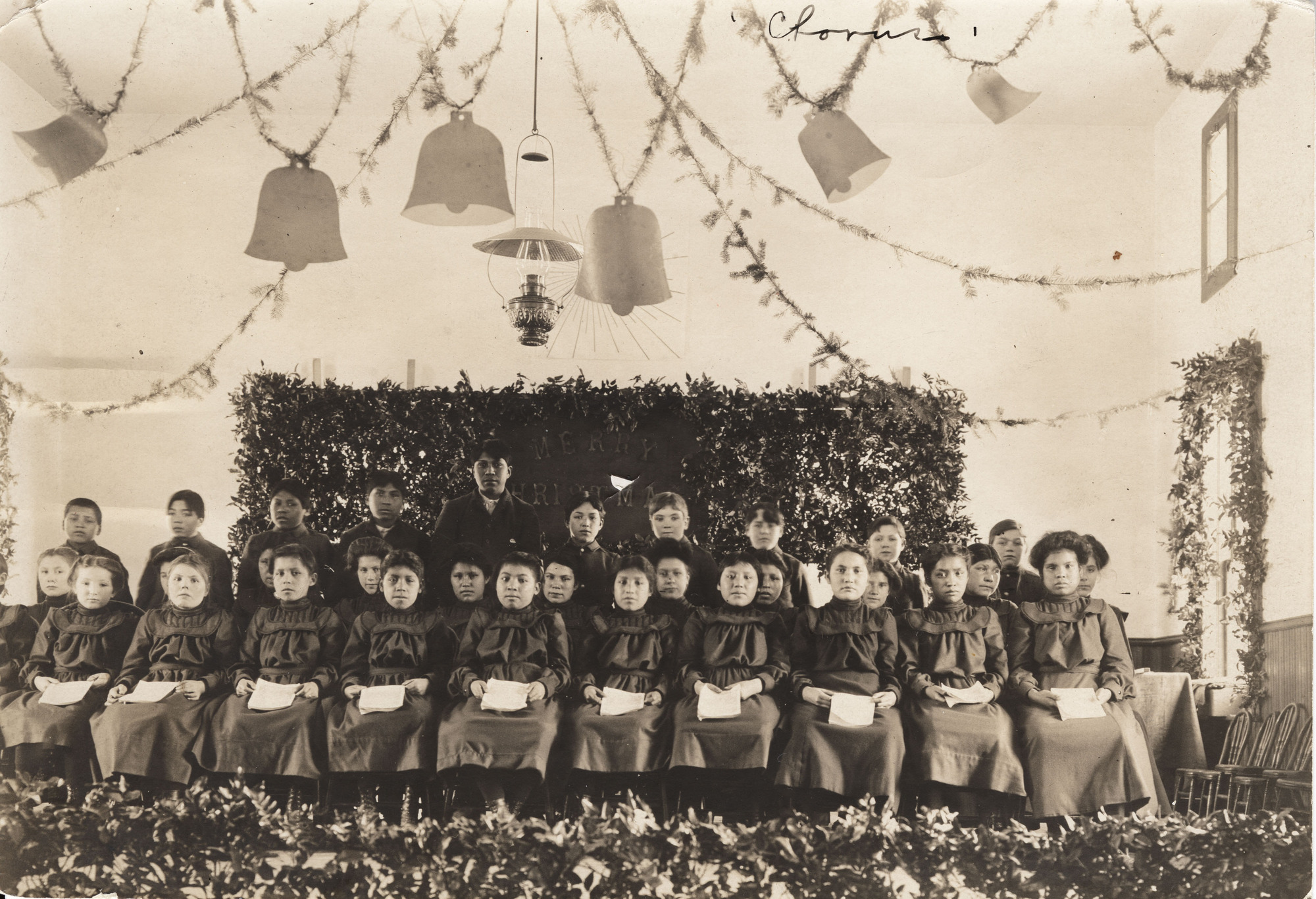 Black and white photograph of identically dressed young children sitting on a stage