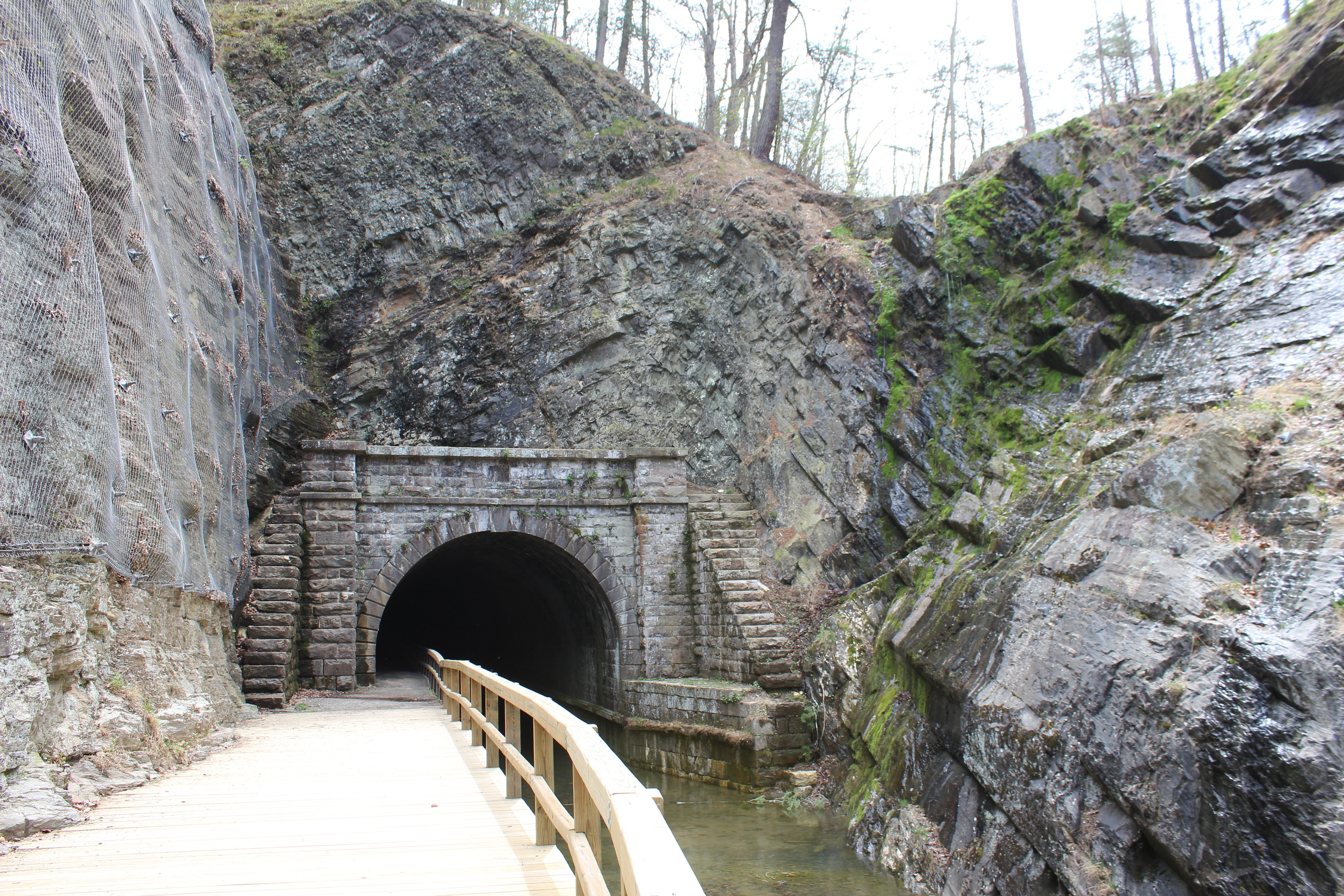 A tunnel opening with a canal and boardwalk entering.