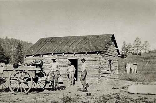 Three people standing outside of a wooden structure