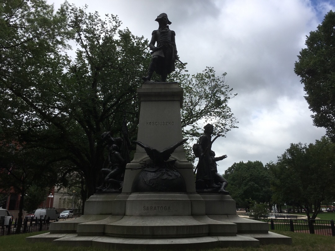 A statue of General Kosciuszko on top of a pedestal, surrounded by other bronze figures