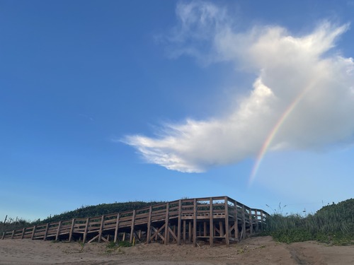 Boardwalk with slight rainbow and clouds.