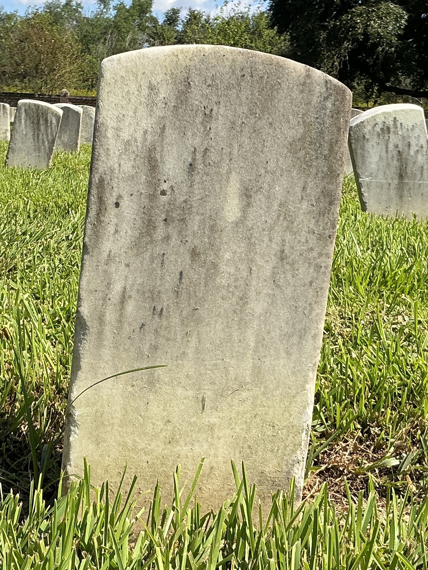 Back of historic upright marble headstone with recessed shield face.