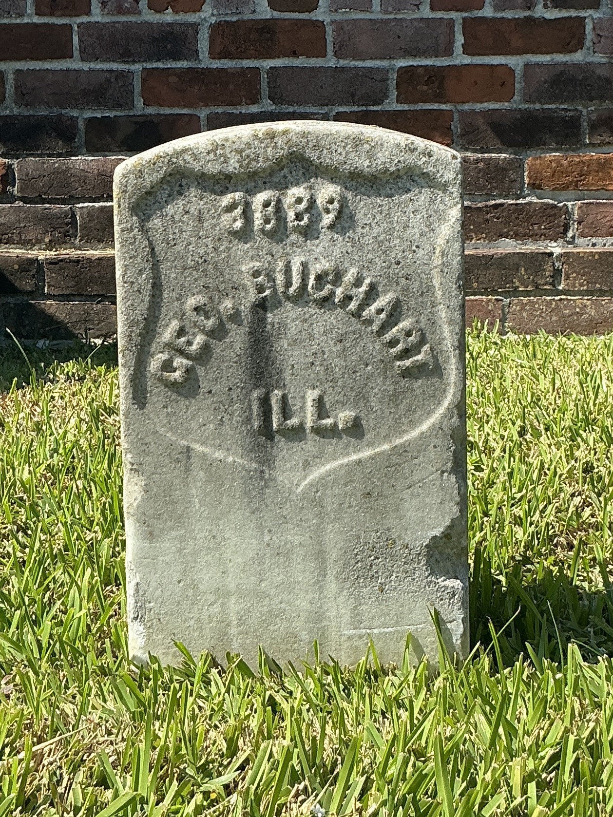 Front of historic upright marble headstone with recessed shield face.