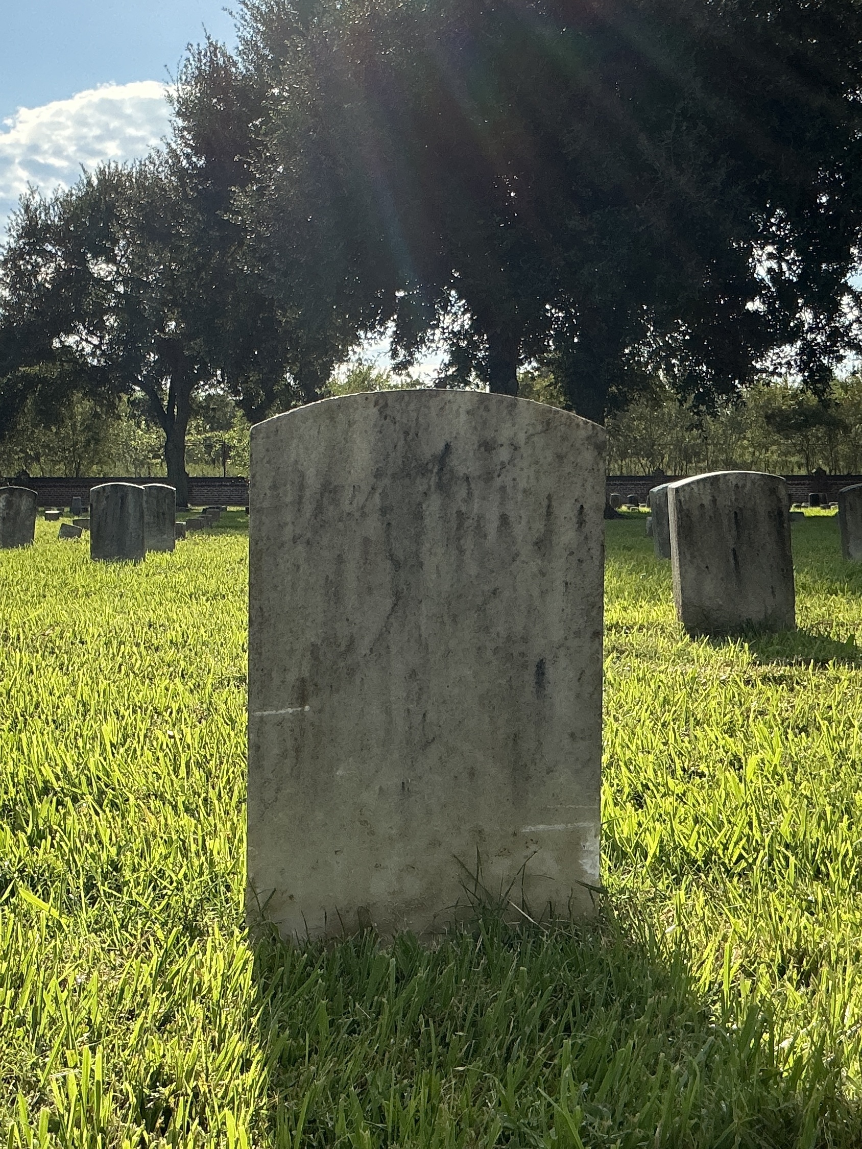 Back of historic upright marble headstone with recessed shield face.