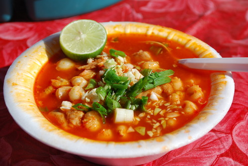 Bowl of red posole with lime