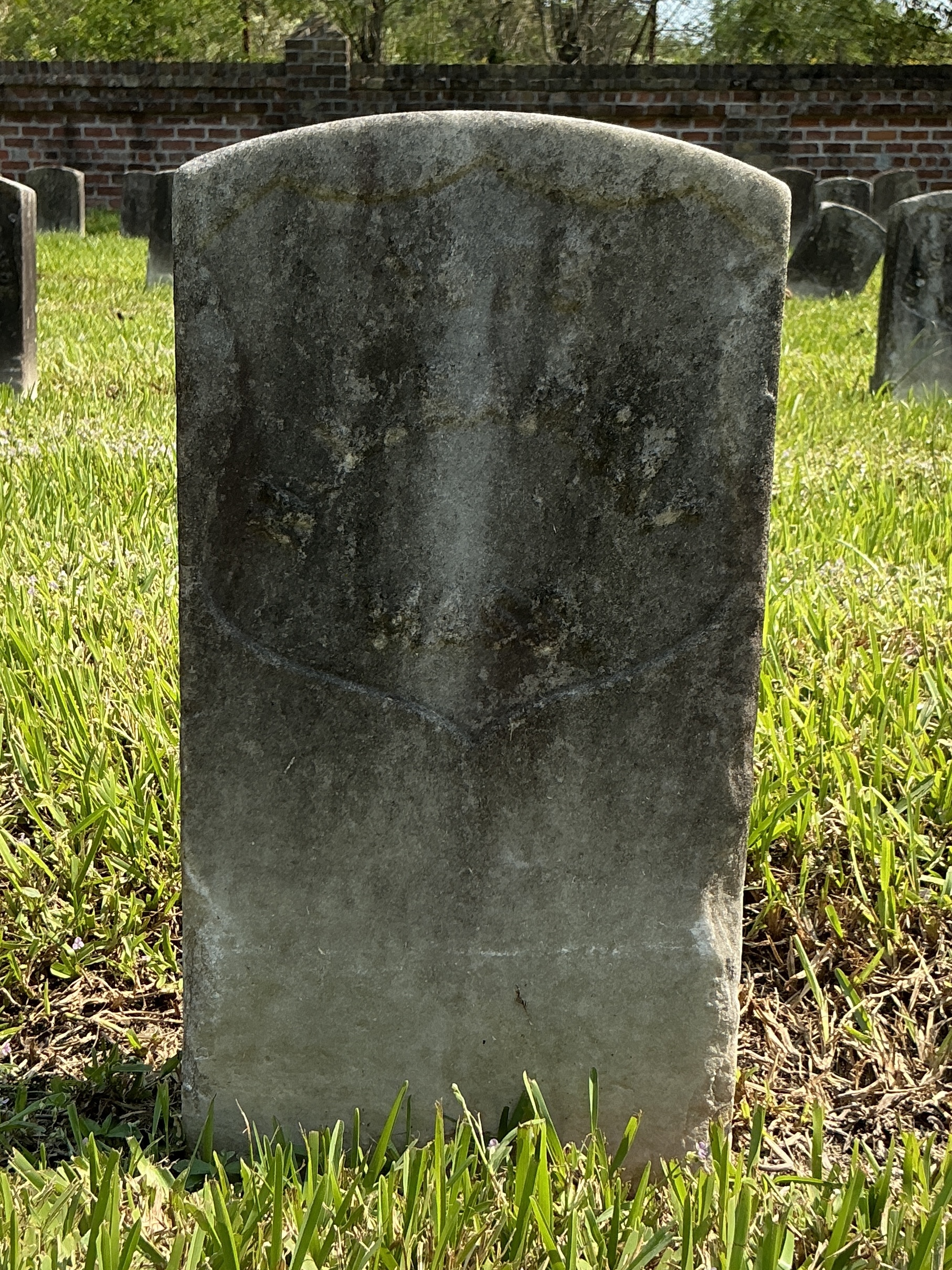 Front of historic upright marble headstone with recessed shield face.