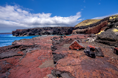 Dramatic rocky shoreline made up of predominately red hardened lava