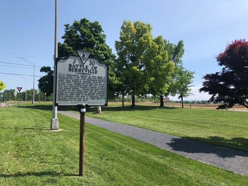 A highway historic marker next to a walking path describes a Civil War battle.