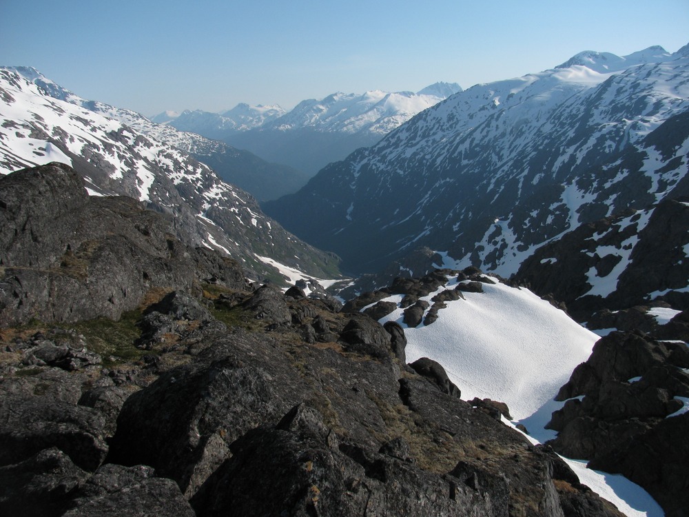 View of a valley from a mountain pass with snowy peaks in the distance