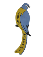 A suffrage bluebird that reads "Votes for Women Nov. 2" on its yellow breast.