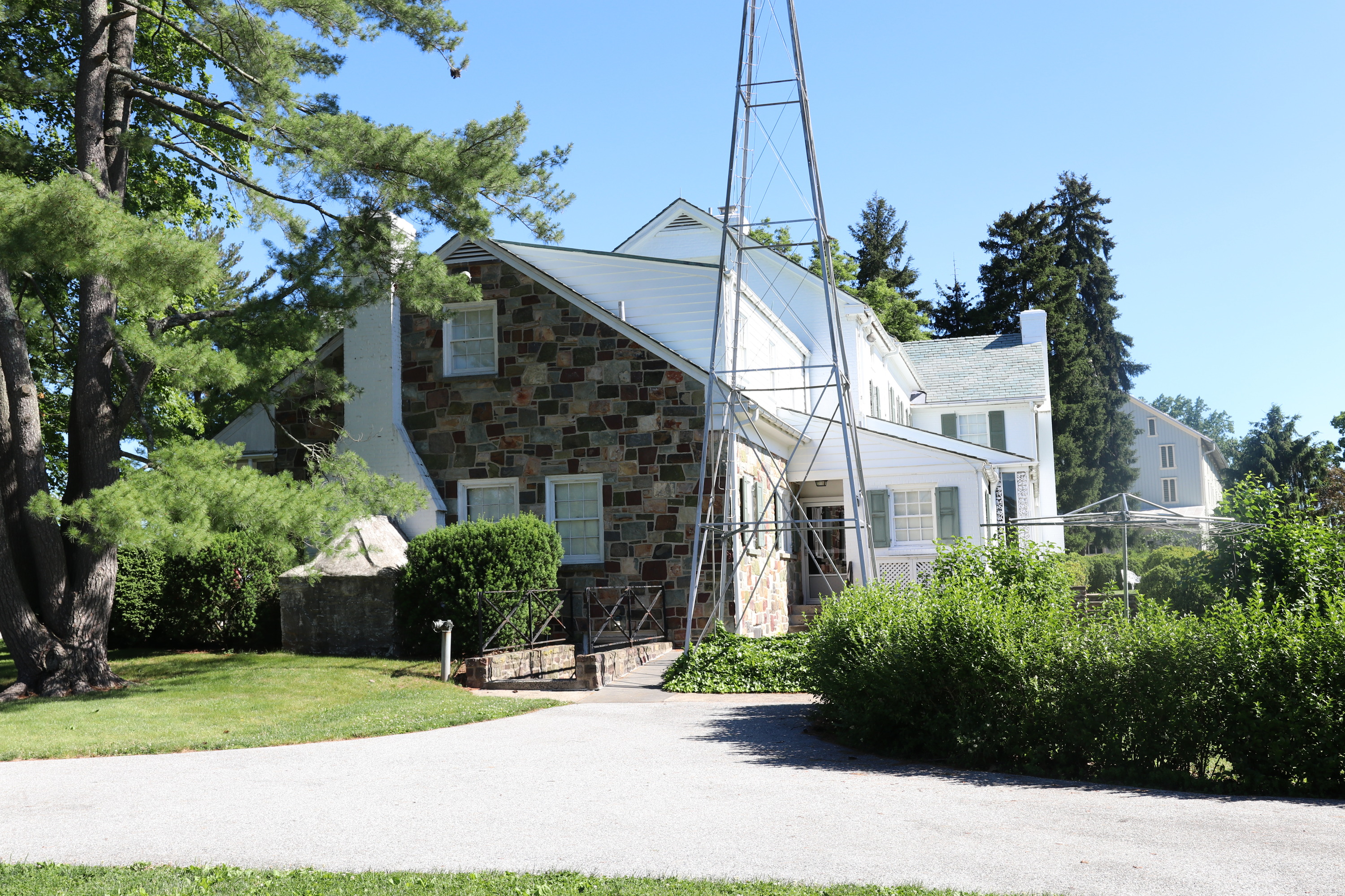 A part stone, part brick house, with a windmill in the foreground. 