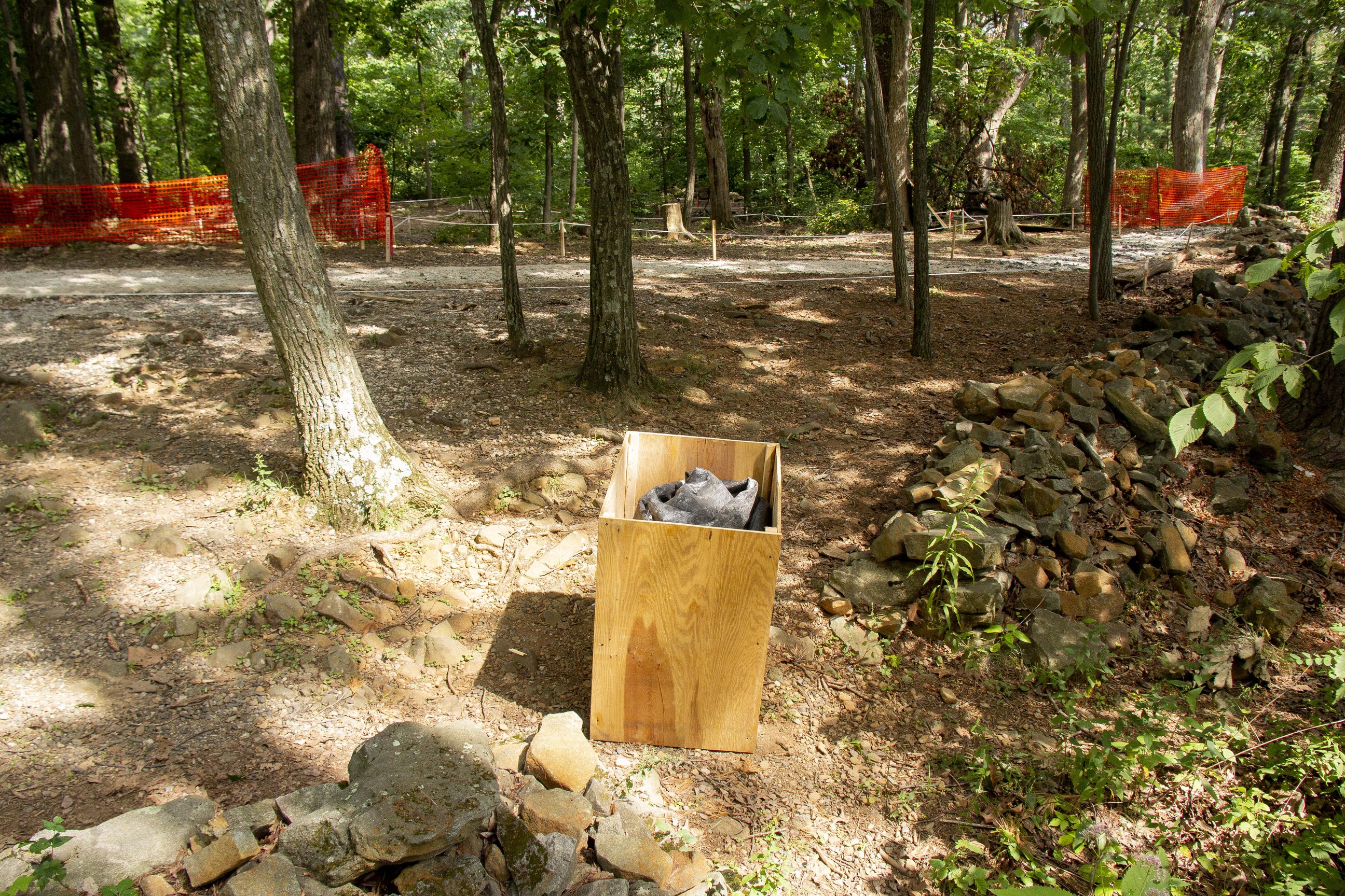 A monument encased in a wooden box in front of a construction site.
