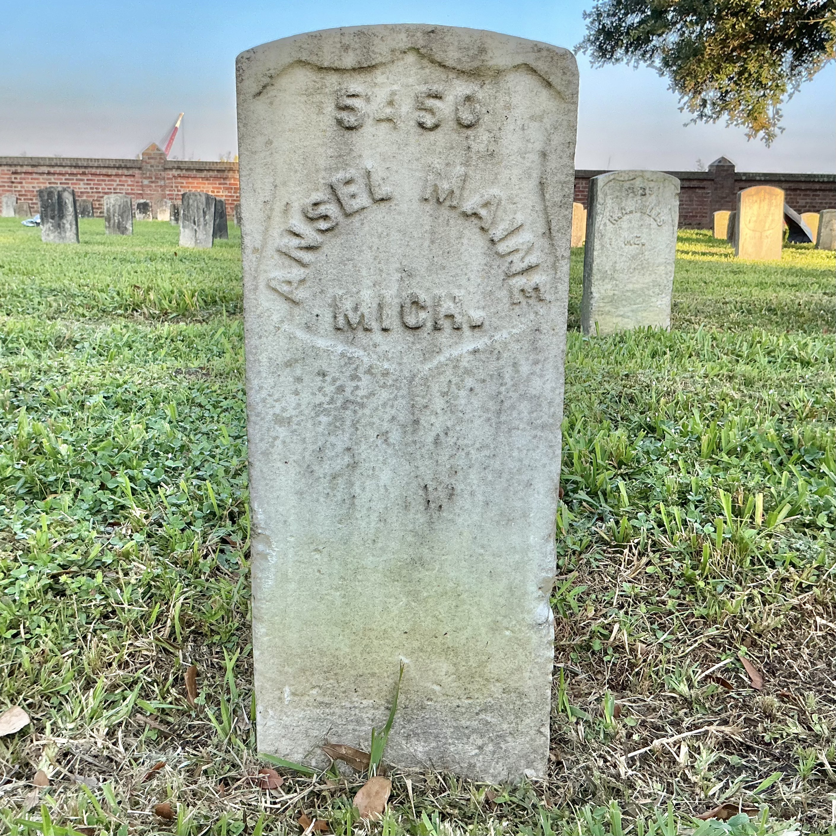 Front of historic upright marble headstone with recessed shield face.