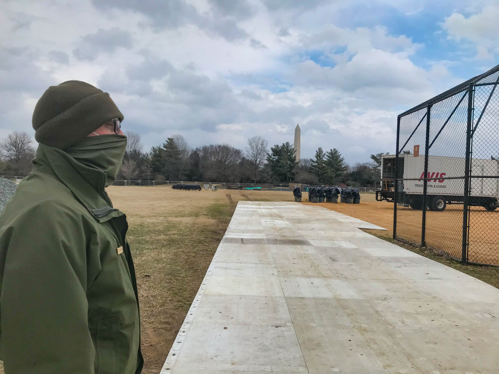 A park ranger looking at event setup on a grass field and softball field