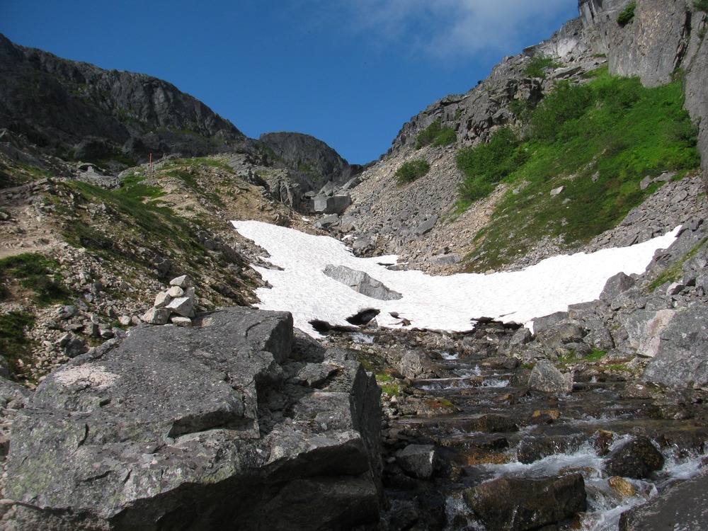 Rocky mountain pass with snow patch in the center.