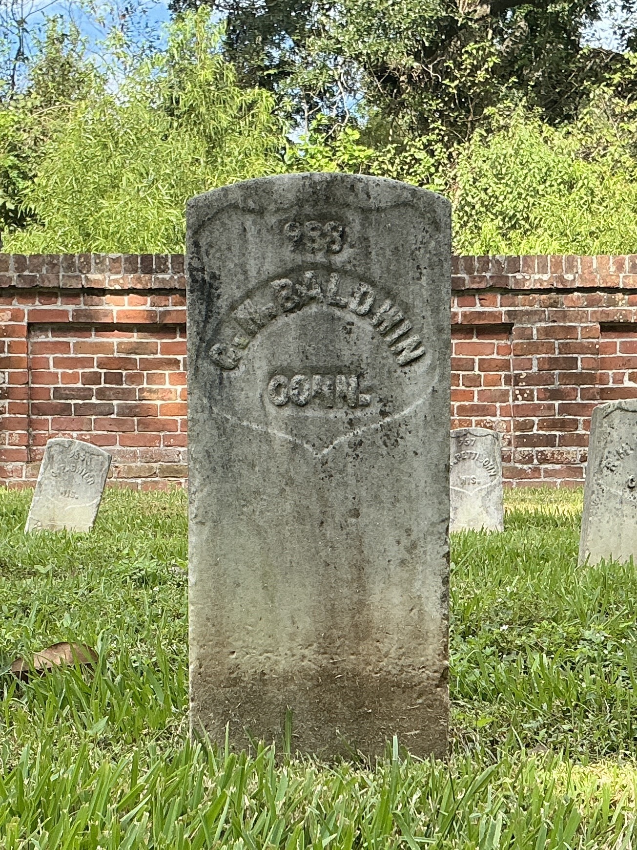 Front of historic upright marble headstone with recessed shield with recessed lettering face.