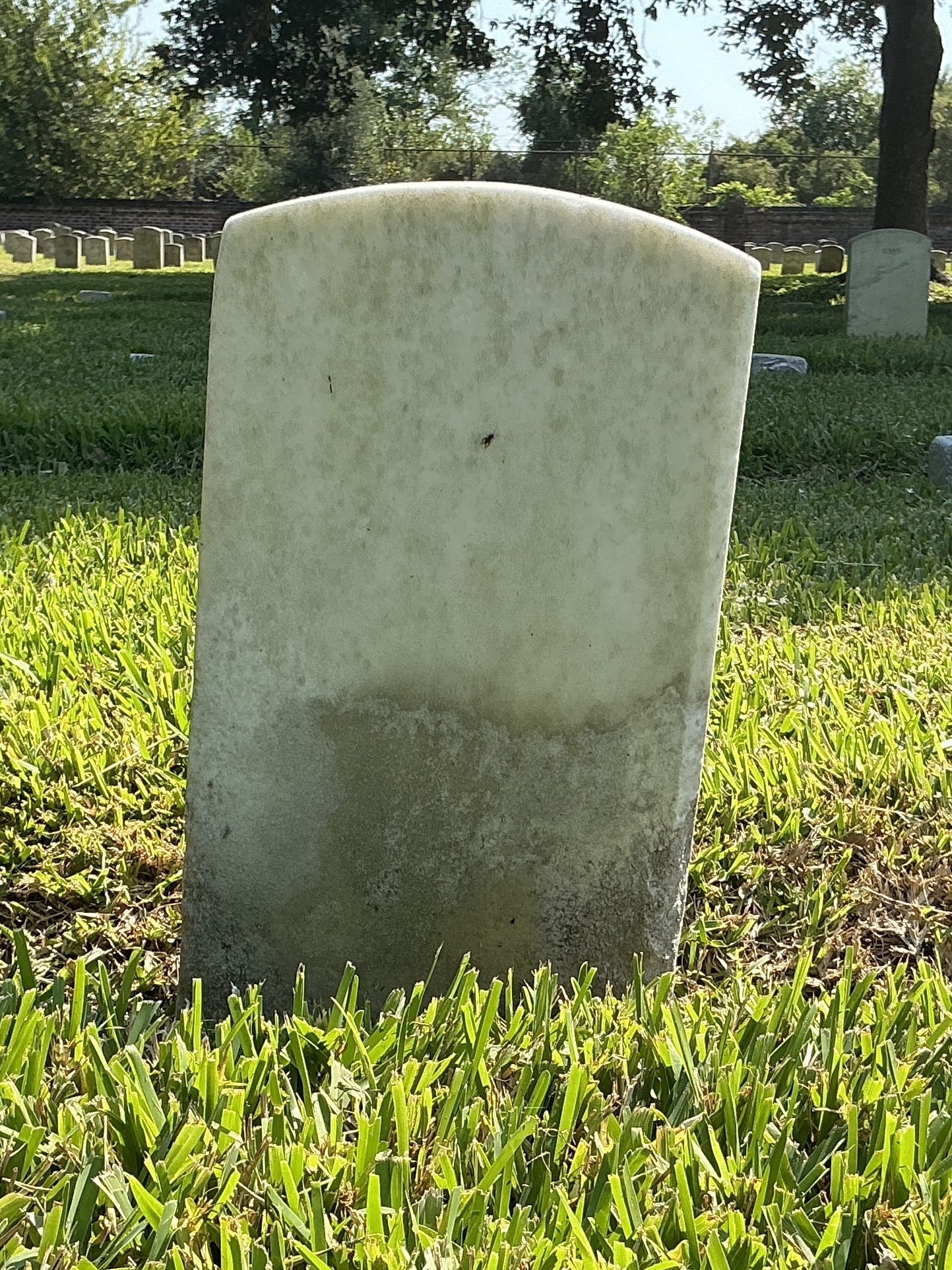Back of historic upright marble headstone with recessed shield face.