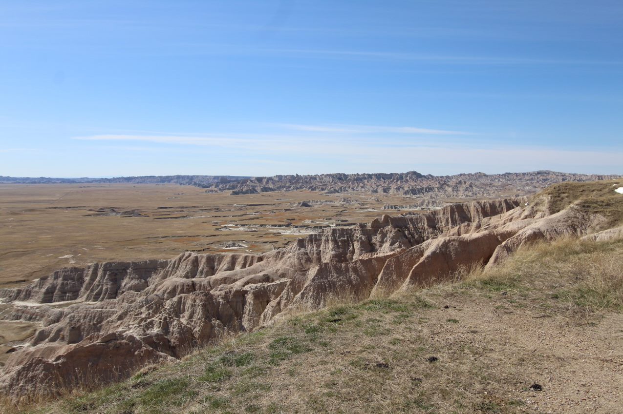 Badlands formations melt into a yellow-orange prairie below