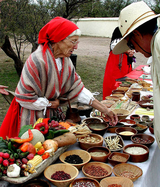 Native food demonstration, table filled with wooden bowls of beans, grains, and produce