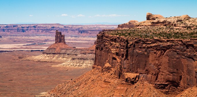 Tall cliffs and rock towers rise above the floor of the desert. 