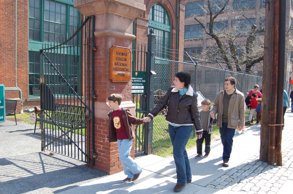 A boy and his mother enter through the main gates to the park.