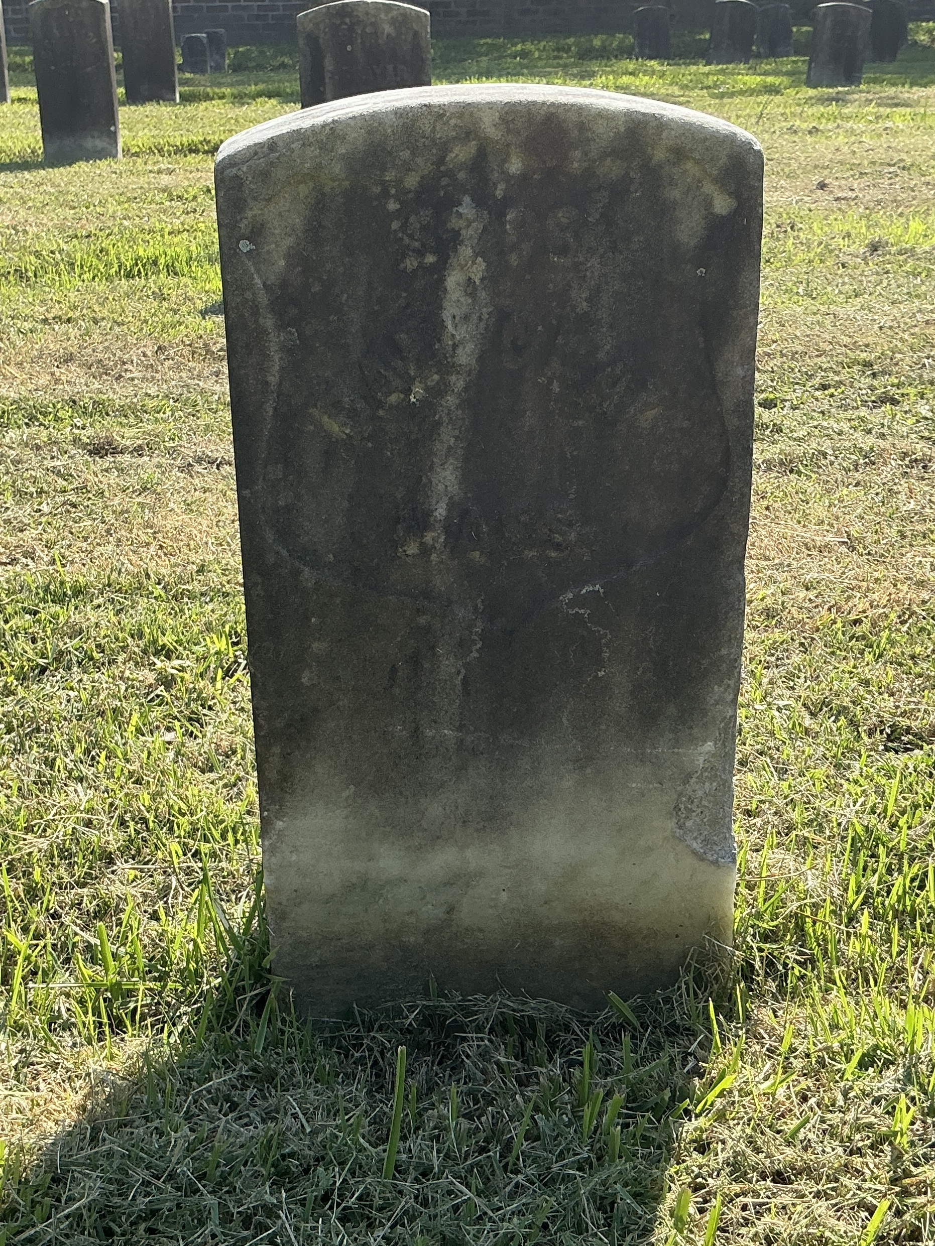 Front of historic upright marble headstone with recessed shield face.