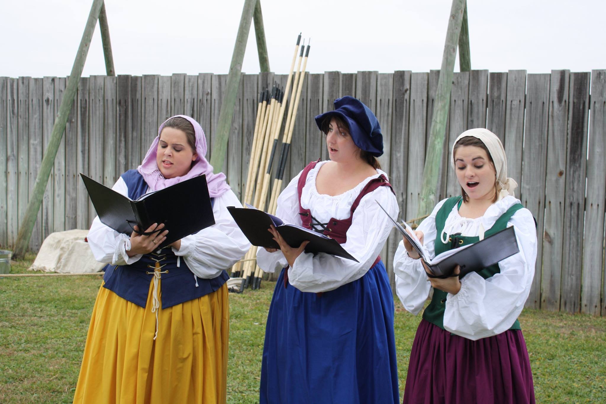 three singers dressed in French bodices, skirts and head coverings