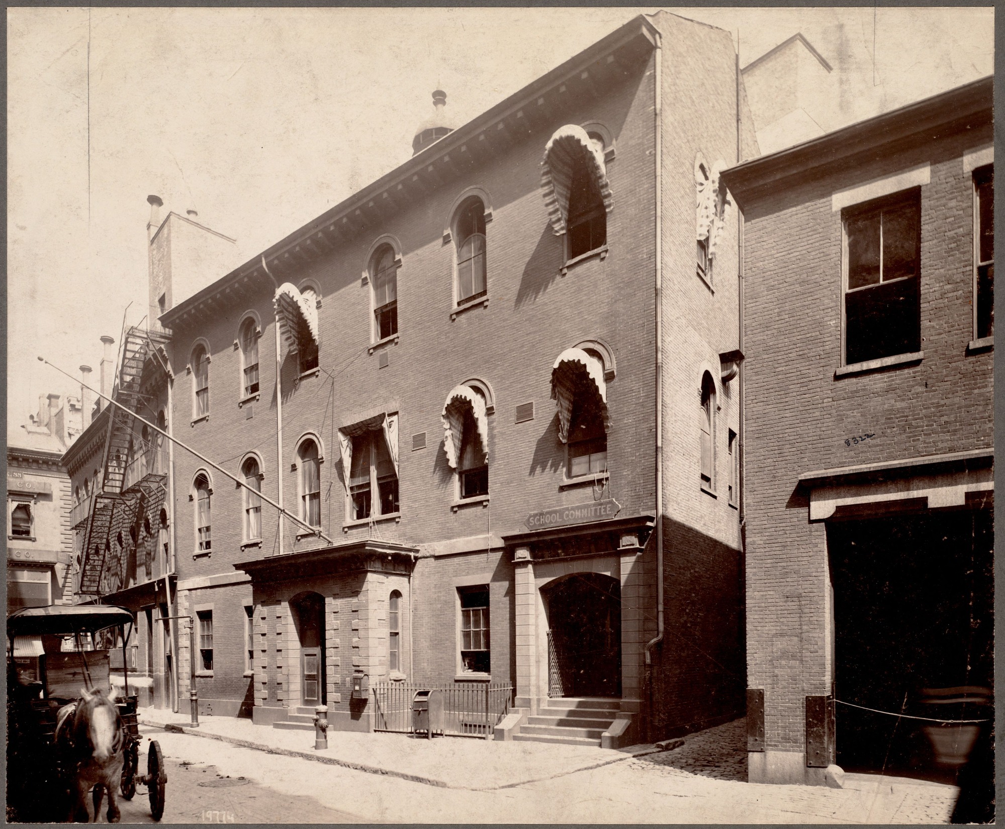 Sepia photograph of a brick building with stone around door entrances that are at the right side of the building and center of the building.