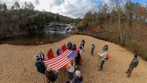 A group of people gathered around holding an American Flag. Photo is a birds eye perspective. 