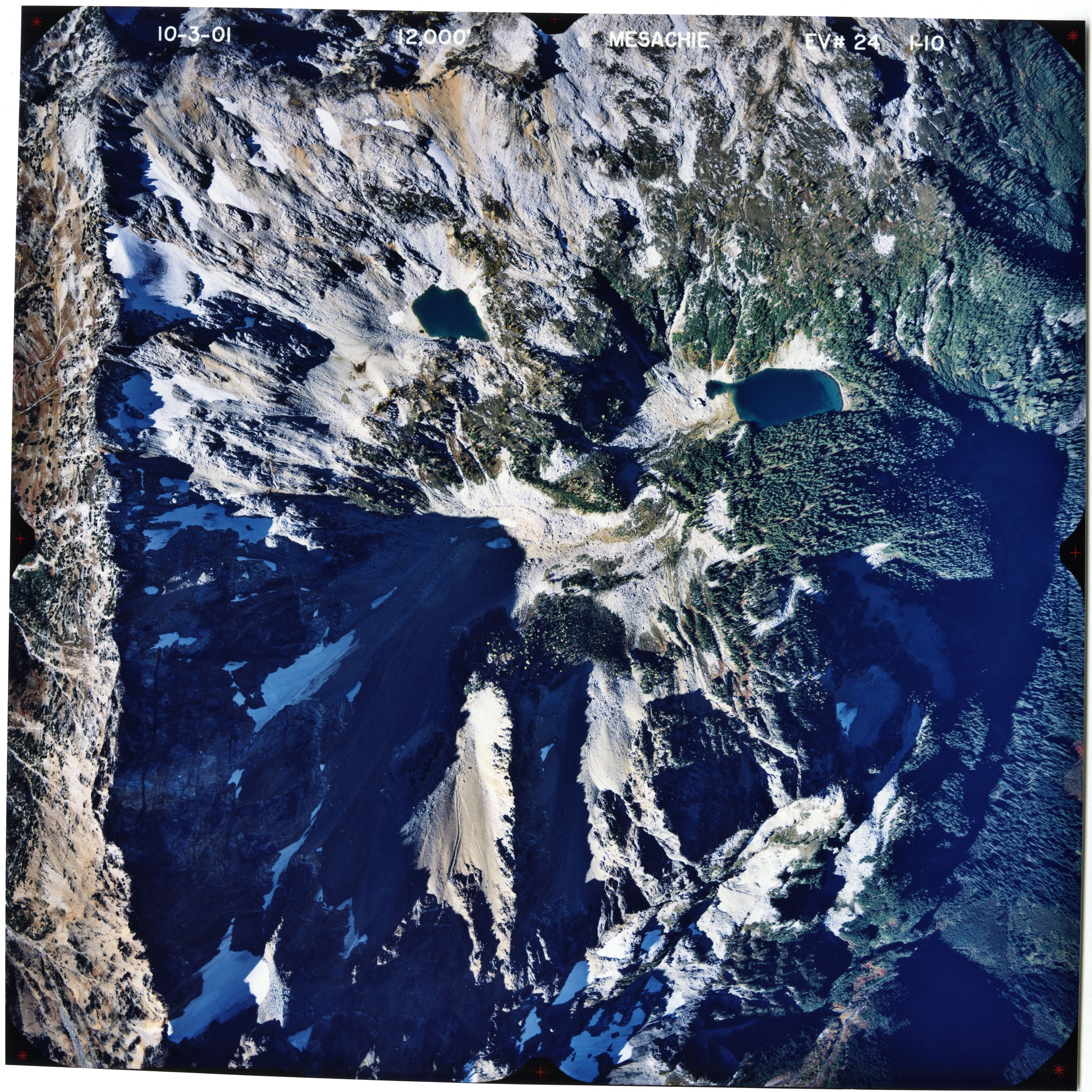 Color aerial photograph of glaciated mountain peak with forested valleys below.